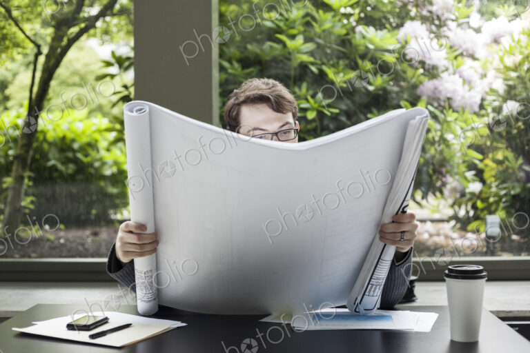 A young hip businessman working on architectural plans in his office.
