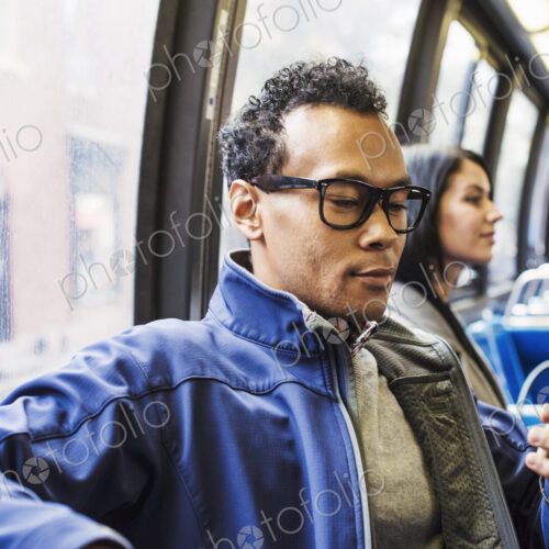 A young man and a young woman sitting on public transport looking at their cellphones. A young man and a young woman sitting on public transport looking at their cellphones.