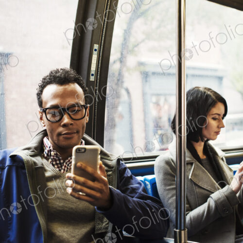 A young man and a young woman sitting on public transport looking at their cellphones. A young man and a young woman sitting on public transport looking at their cellphones.