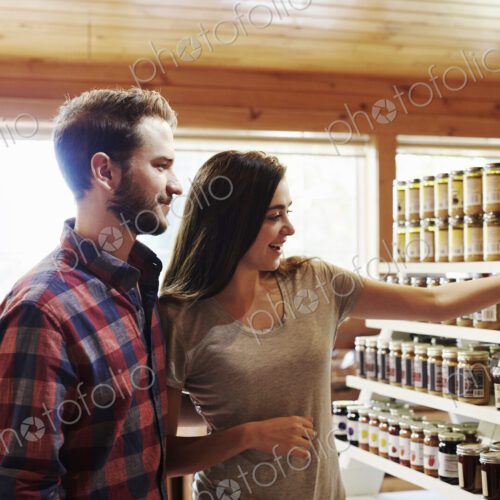 A young man and woman choosing from a display of canned produce in a farm shop.