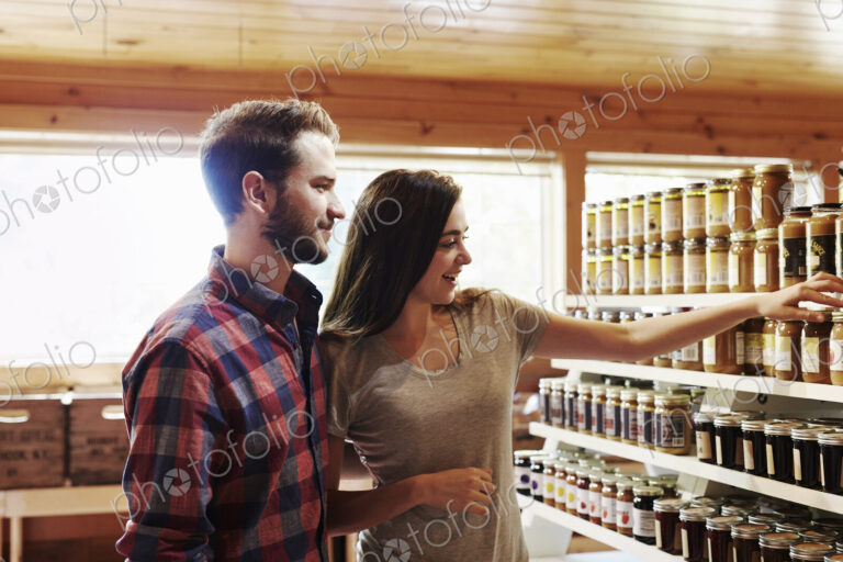 A young man and woman choosing from a display of canned produce in a farm shop.