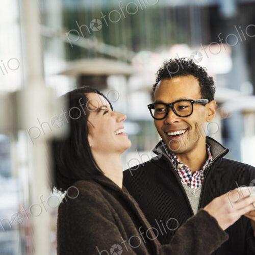 A young man and woman holding a cellphone together and laughing. A young man and woman holding a cellphone together and laughing.