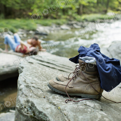 A young man and woman on the rocks on a river bank. Jeans and boots on a rock. A young man and woman on the rocks on a river bank. Jeans and boots on a rock.