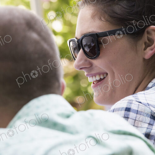 A young man and woman sitting side by side, smiling.