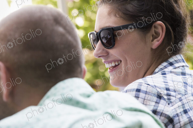A young man and woman sitting side by side, smiling.