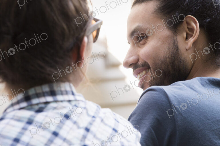 A young man and woman sitting side by side, smiling and talking.