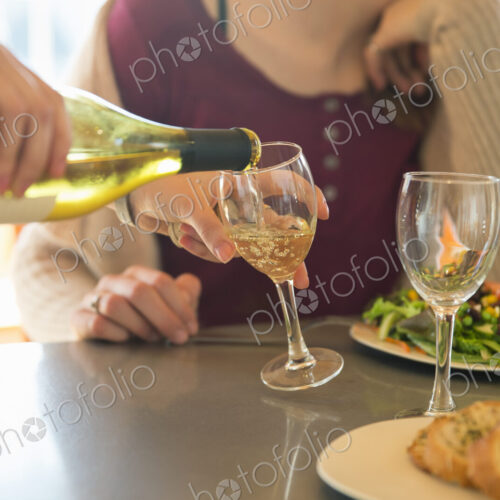 A young man and woman sitting together having a meal and drinking wine.