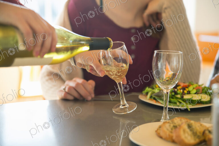 A young man and woman sitting together having a meal and drinking wine.
