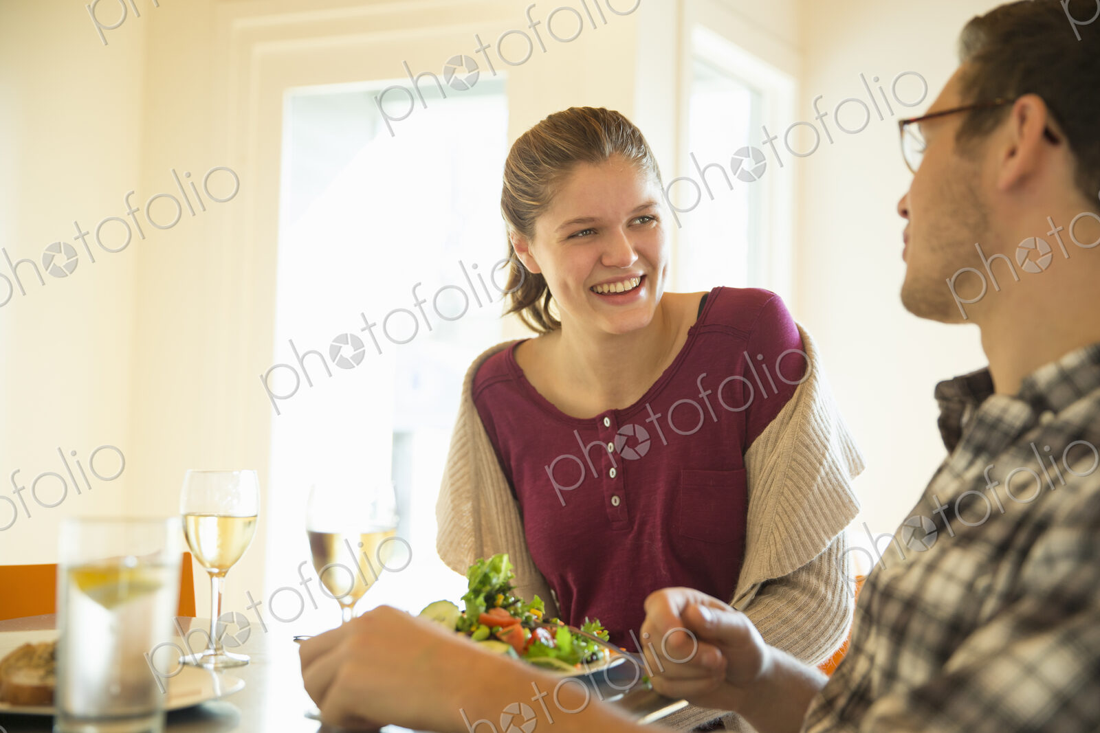 A young man and woman sitting together having a meal and drinking wine.