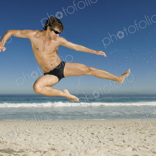 A young man doing a karate style leap on the beach in Cape Town. A young man doing a karate style leap on the beach in Cape Town.