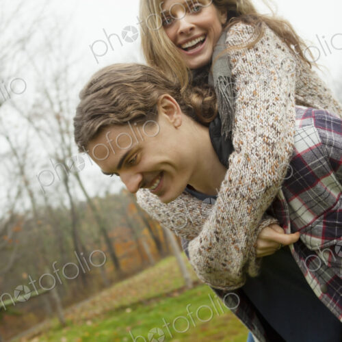 A young man giving a woman a piggyback. An organic farm setting.