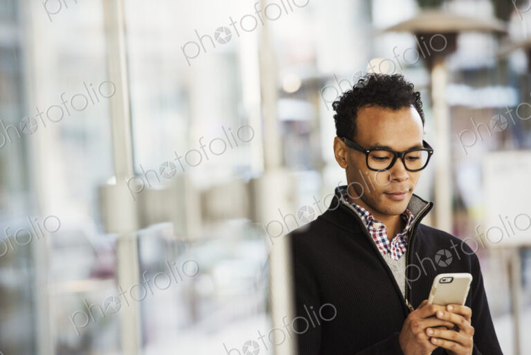 A young man holding at a cellphone and smiling.