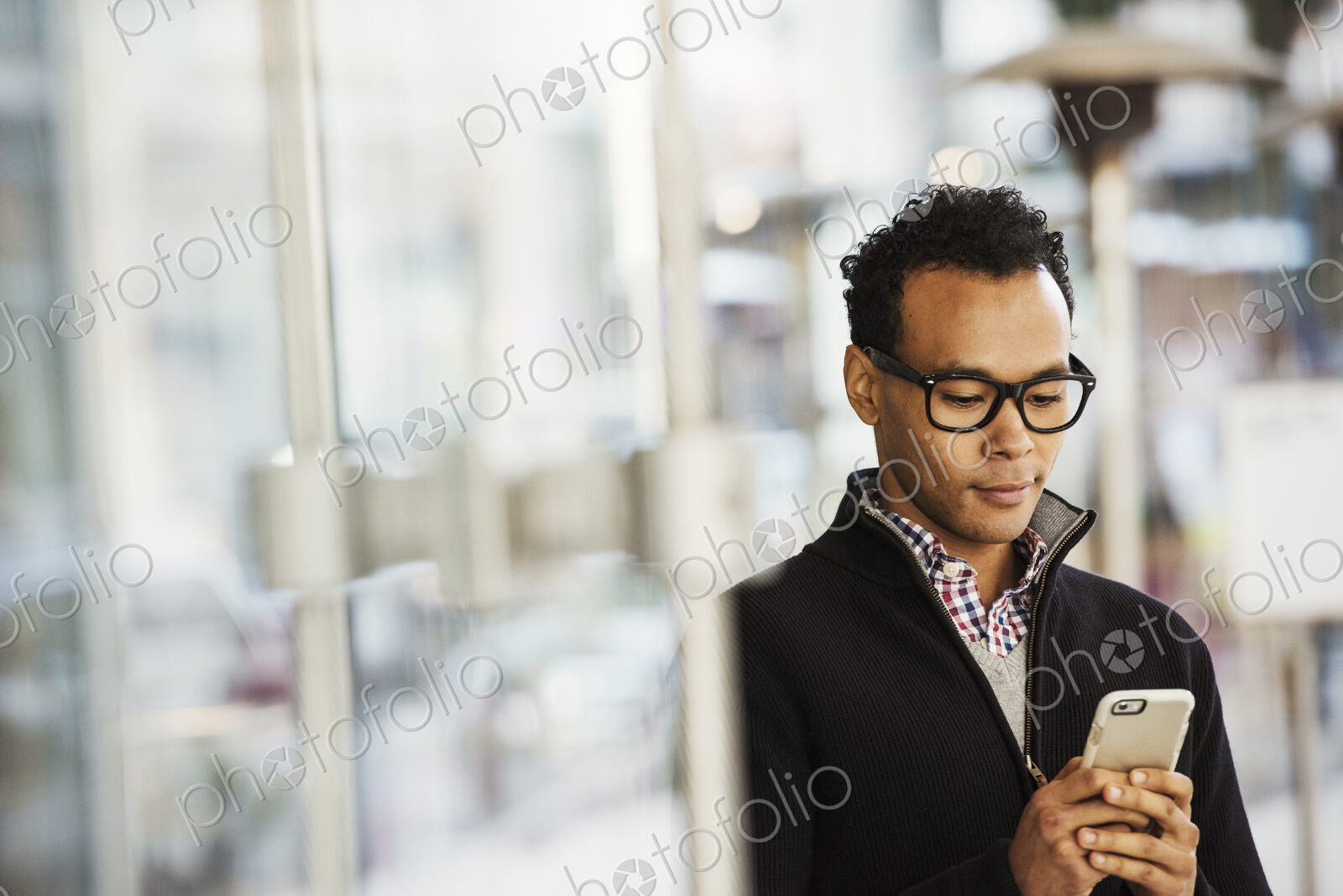 A young man holding at a cellphone and smiling.