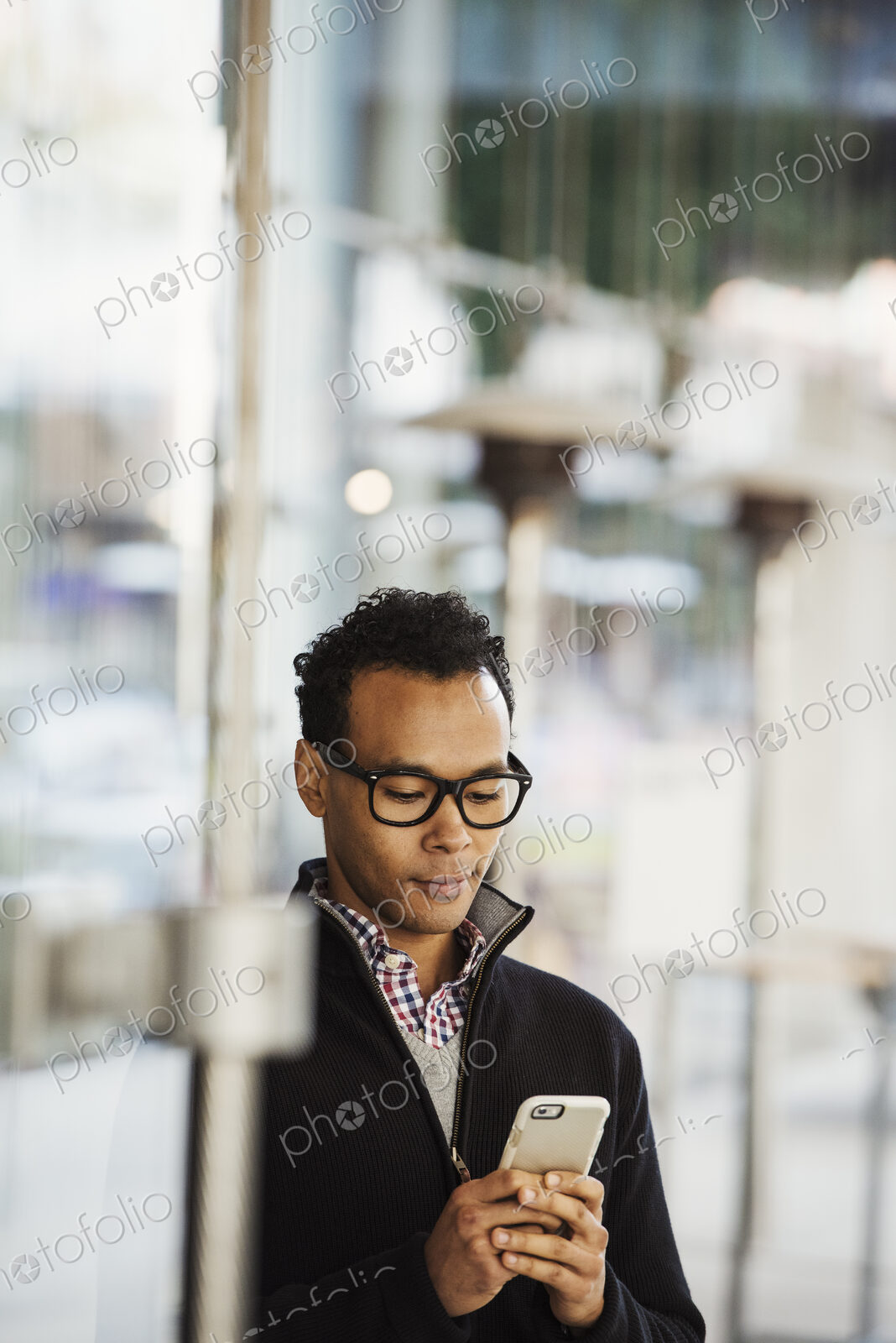 A young man holding at a cellphone and smiling.