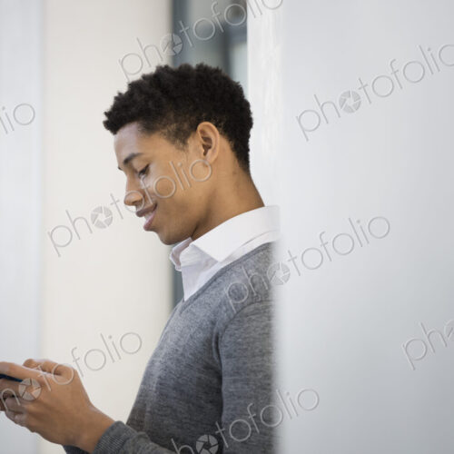 A young man in a grey sweater using his mobile phone.