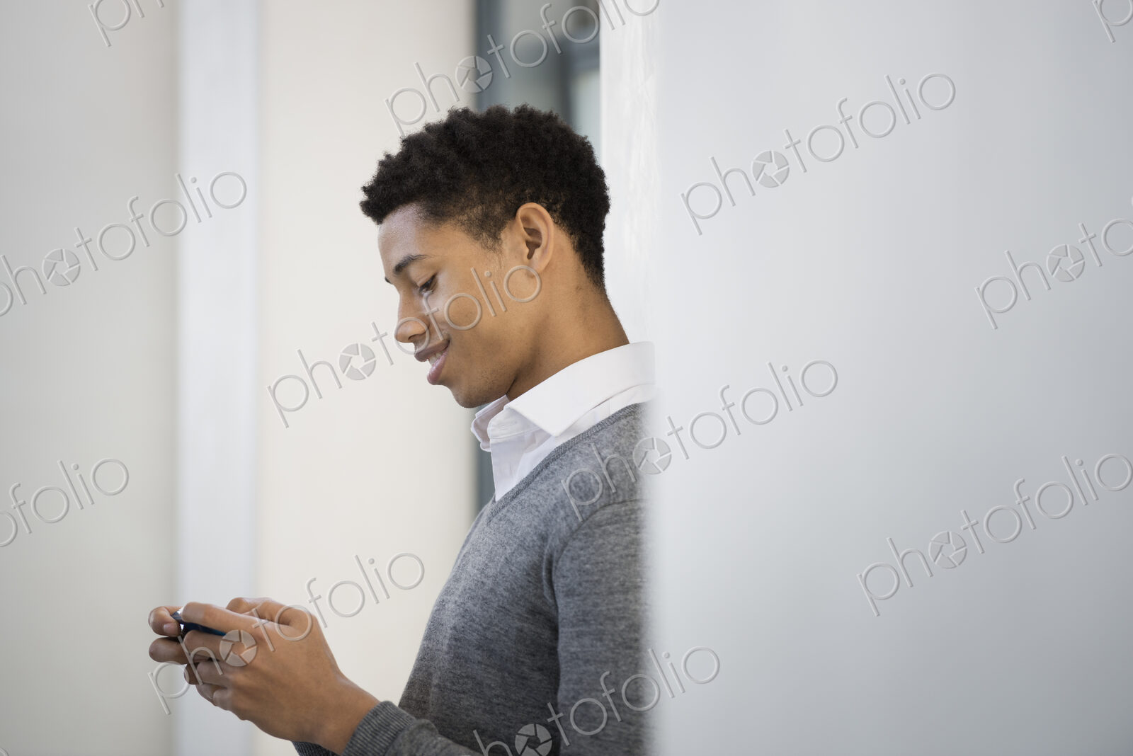 A young man in a grey sweater using his mobile phone.