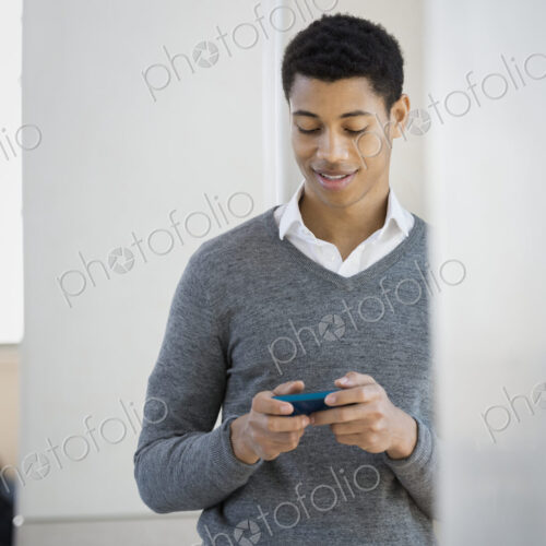 A young man in a grey sweater using his mobile phone. A young man in a grey sweater using his mobile phone.