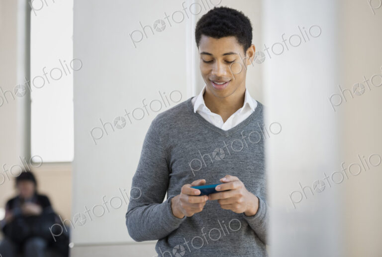 A young man in a grey sweater using his mobile phone.