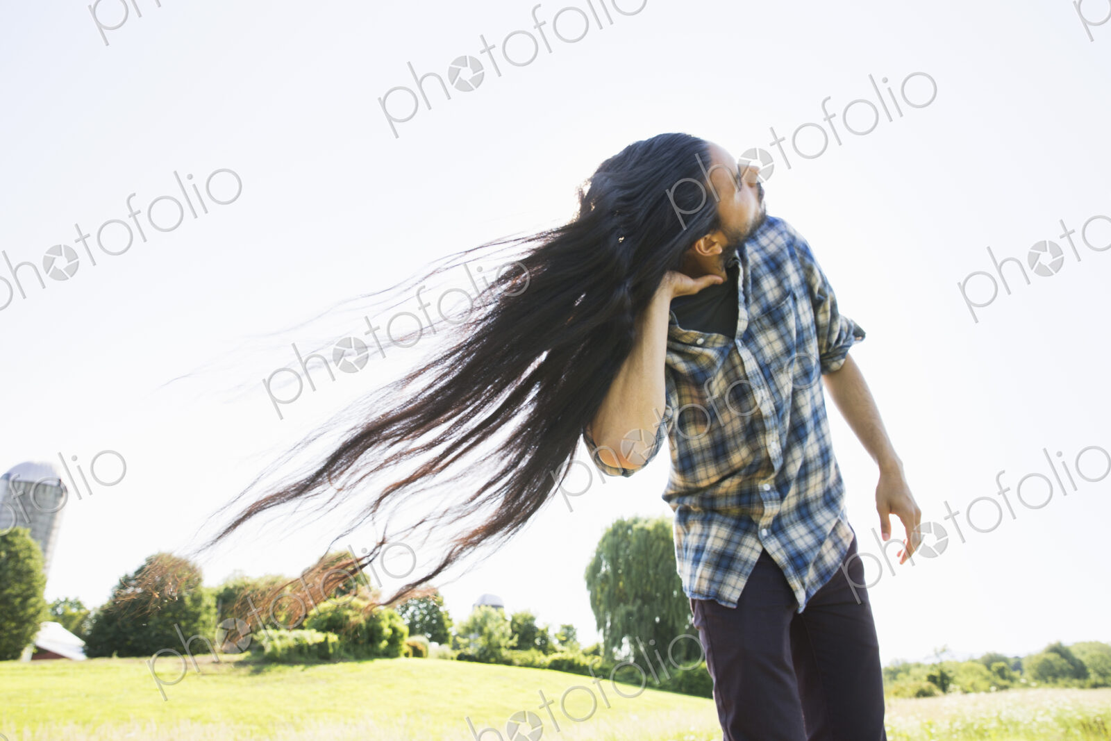 A young man shaking his head with his long hair flowing in the breeze.