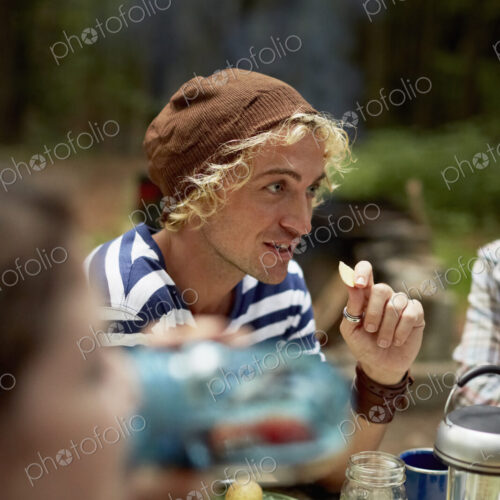 A young man sitting at a picnic table in the woods. A young man sitting at a picnic table in the woods.