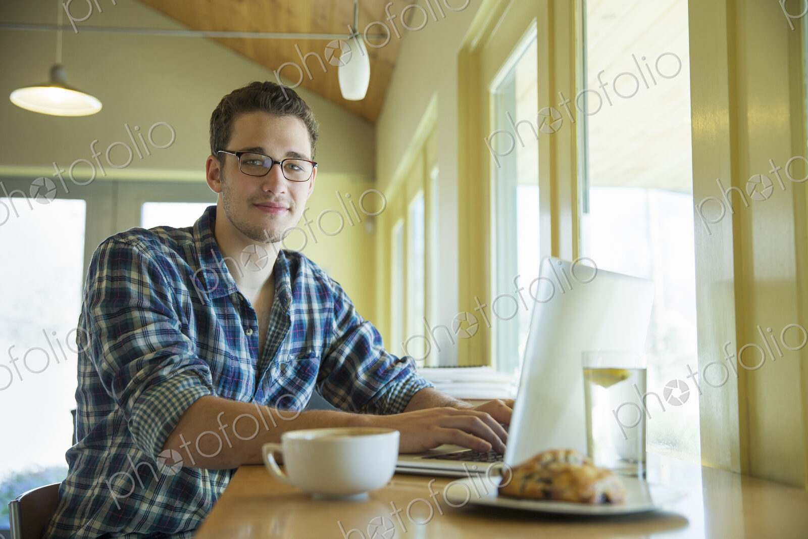 A young man sitting at a table using a laptop computer.
