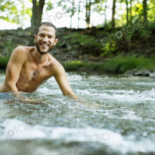 A young man swimming in a fast flowing cooling stream. A young man swimming in a fast flowing cooling stream.