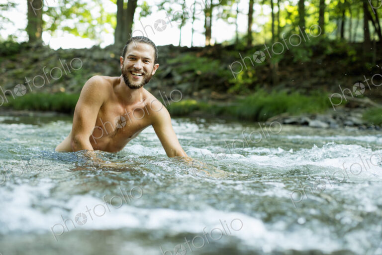 A young man swimming in a fast flowing cooling stream.
