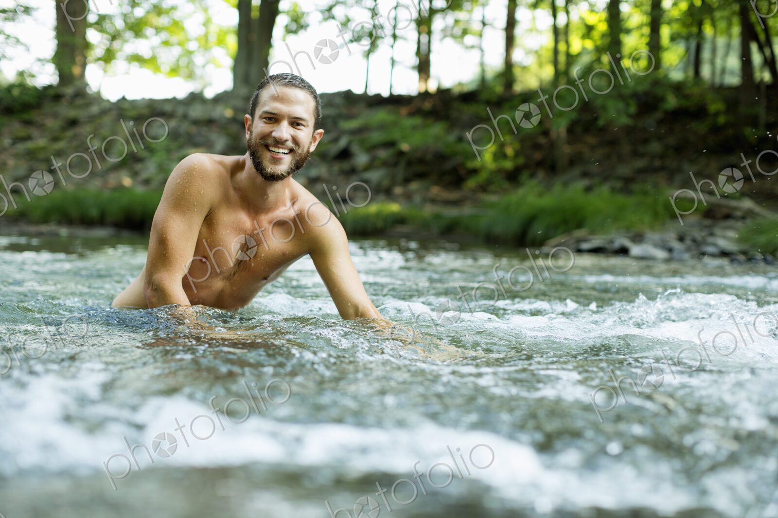 A young man swimming in a fast flowing cooling stream.