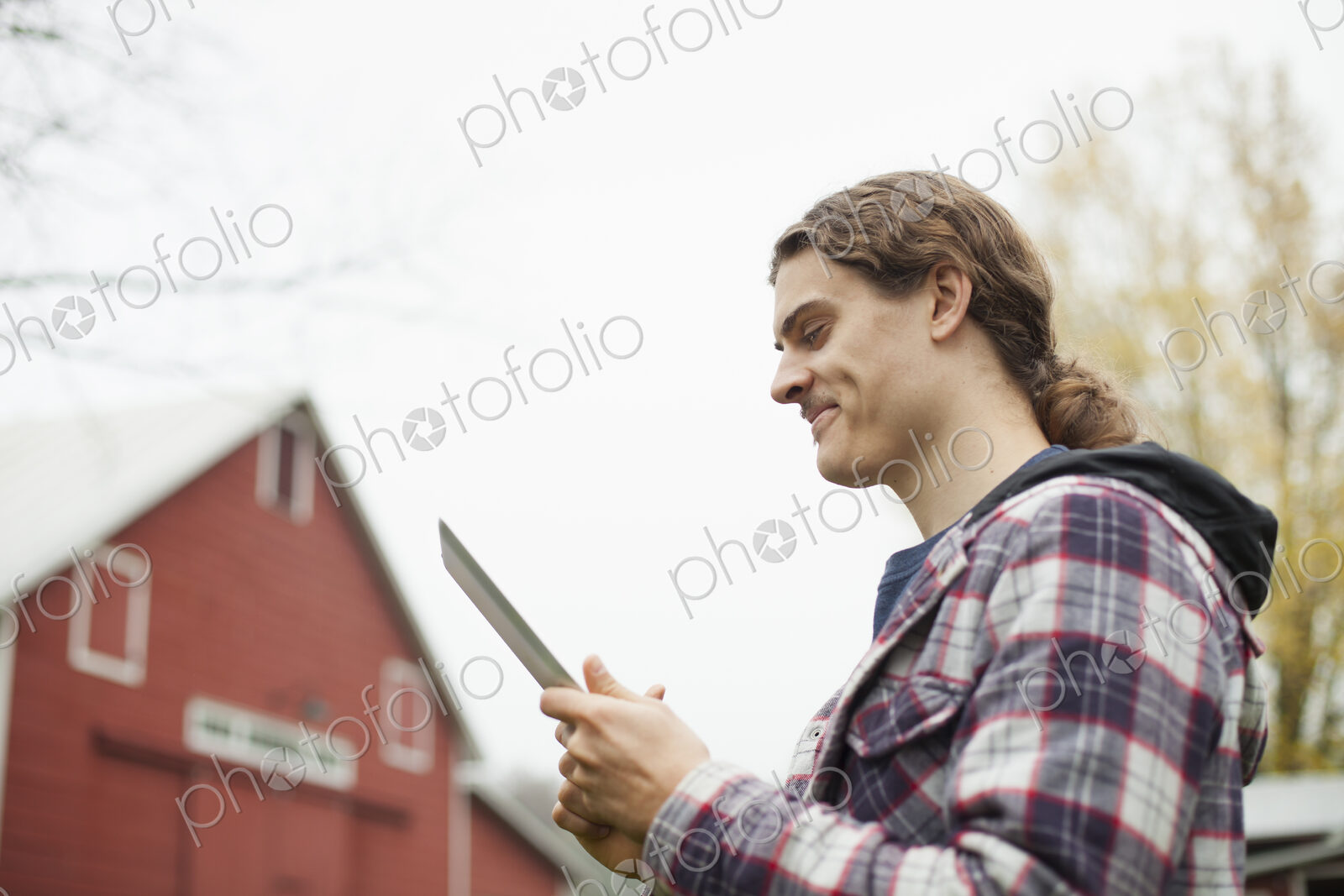A young man using a computer tablet, a portable PC tablet device, on an organic farm.
