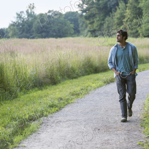 A young man walking down a path with his hands in his pockets. A young man walking down a path with his hands in his pockets.