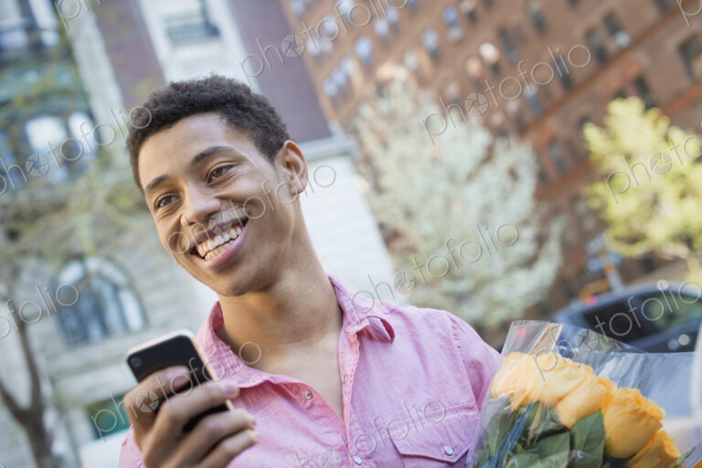 A young man wearing a pink casual shirt with a smart phone