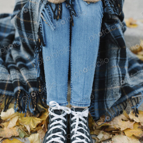 A young person sitting on a step with a warm plaid shawl around her.