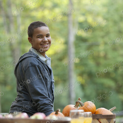 A young person sitting outside in fresh air, at a table laid for a meal.