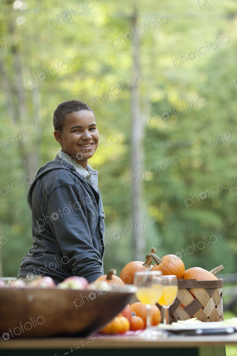 A young person sitting outside in fresh air, at a table laid for a meal.