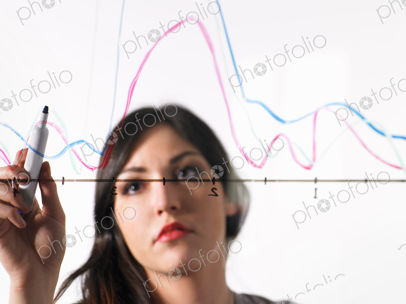A young woman drawing coloured graph lines across a graph illustration, on a see…