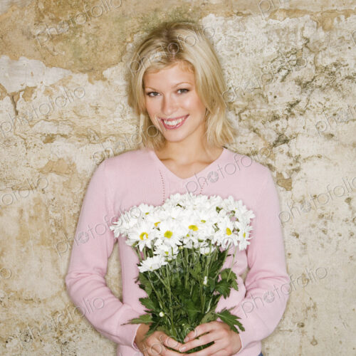 A young woman holding a bunch of daisies. A young woman holding a bunch of daisies.