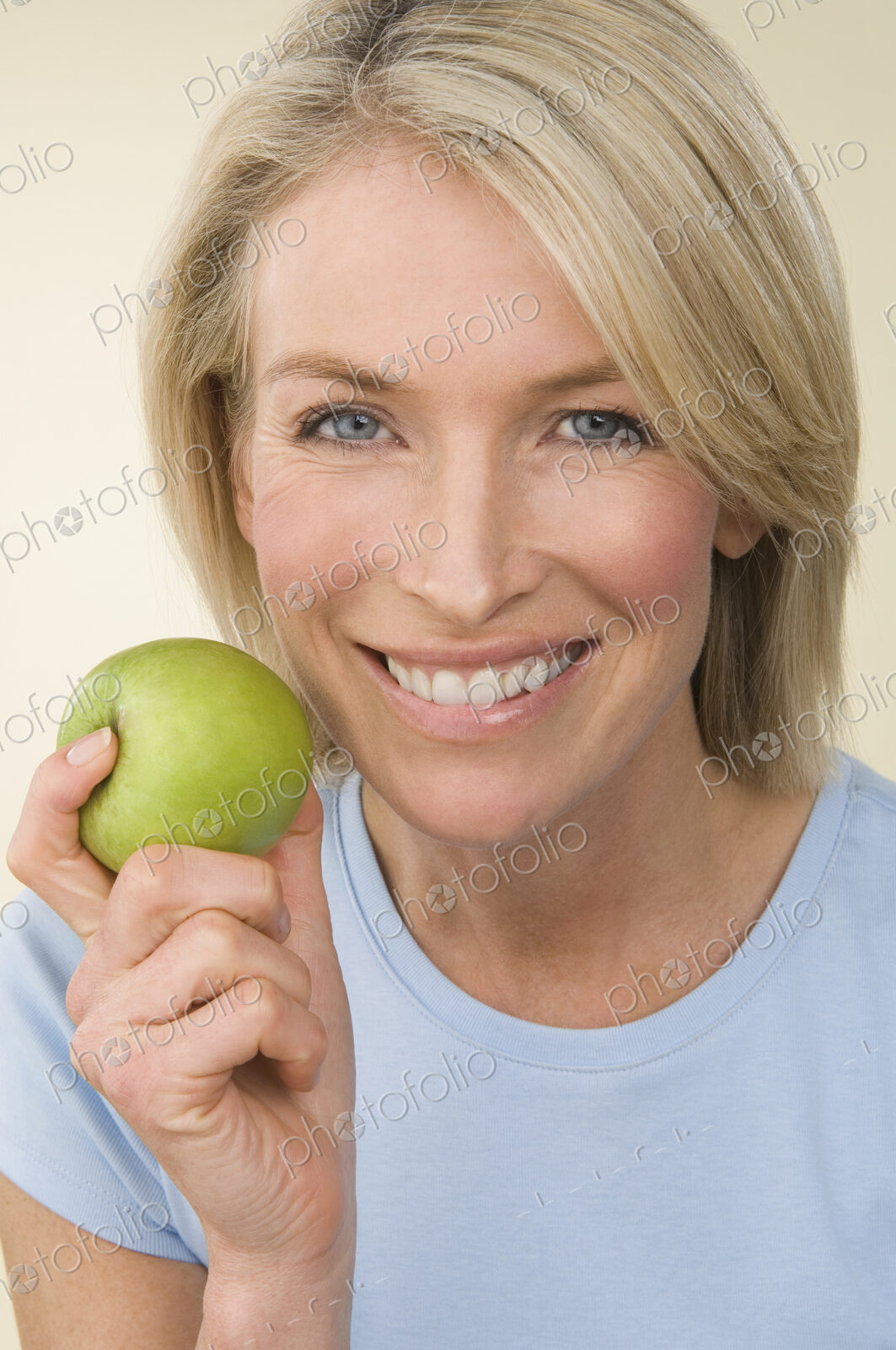 A young woman holding a green apple.