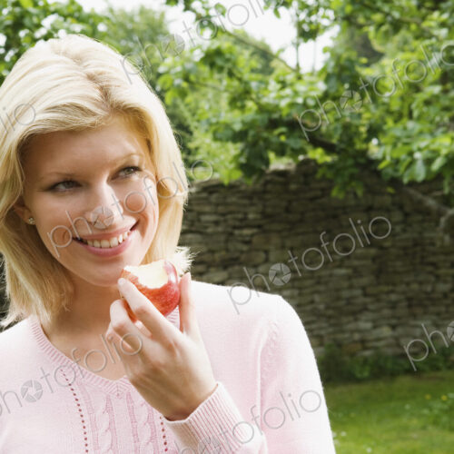 A young woman holding a half eaten apple. A young woman holding a half eaten apple.