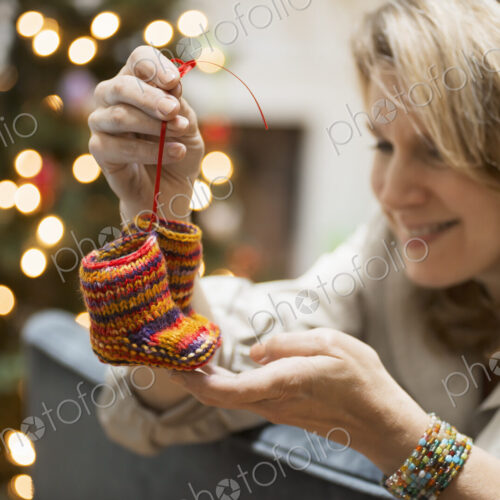 A young woman holding a pair of hand knitted baby booties. A young woman holding a pair of hand knitted baby booties.
