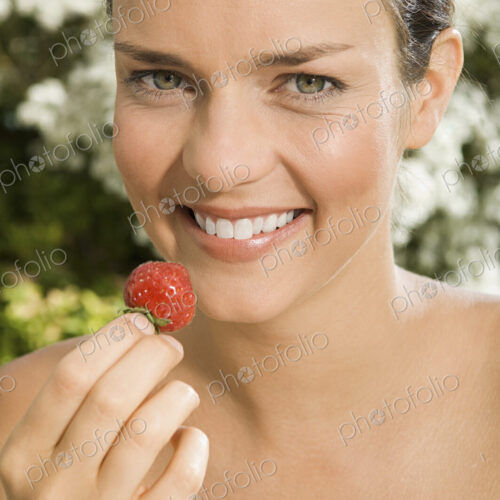 A young woman holding a strawberry. A young woman holding a strawberry.