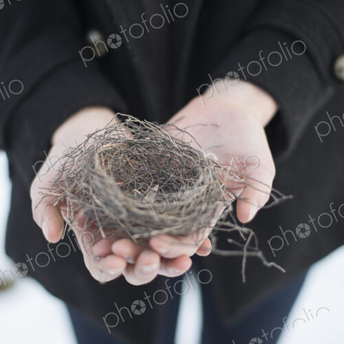A young woman holding an old bird's nest in her hands, tightly woven twigs. Winter scene. A young woman holding an old bird's nest in her hands, tightly woven twigs. Winter scene.