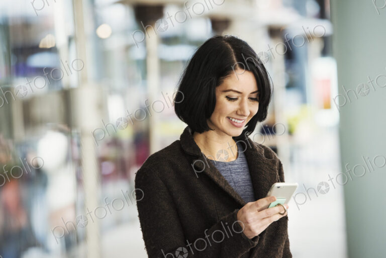 A young woman holding at a cellphone and smiling.