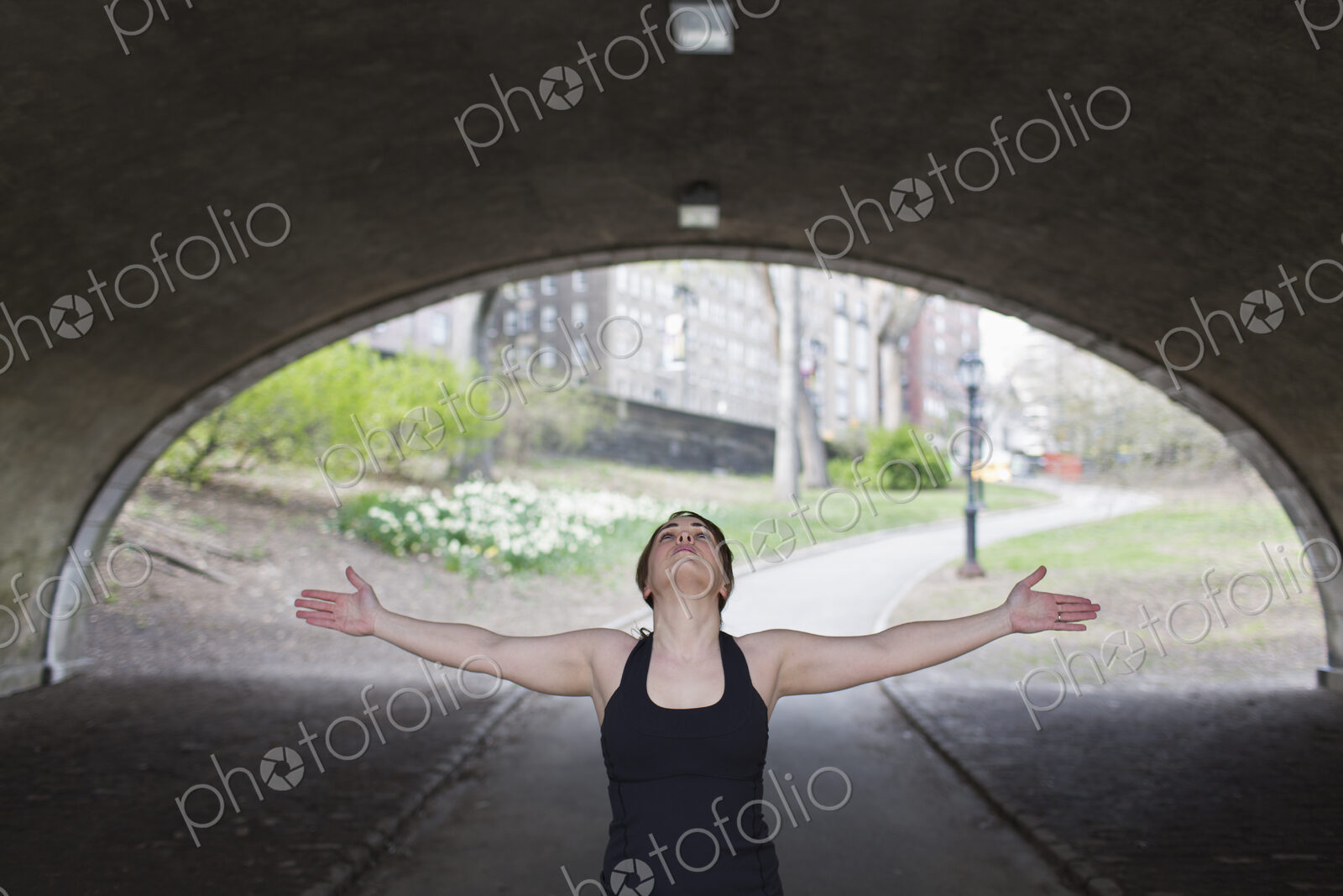 A young woman in Central Park, in a black leotard and leggings, doing yoga.