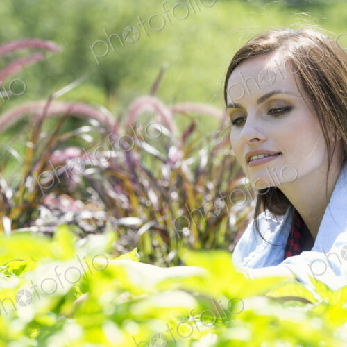 A young woman in a garden examining growing plants.