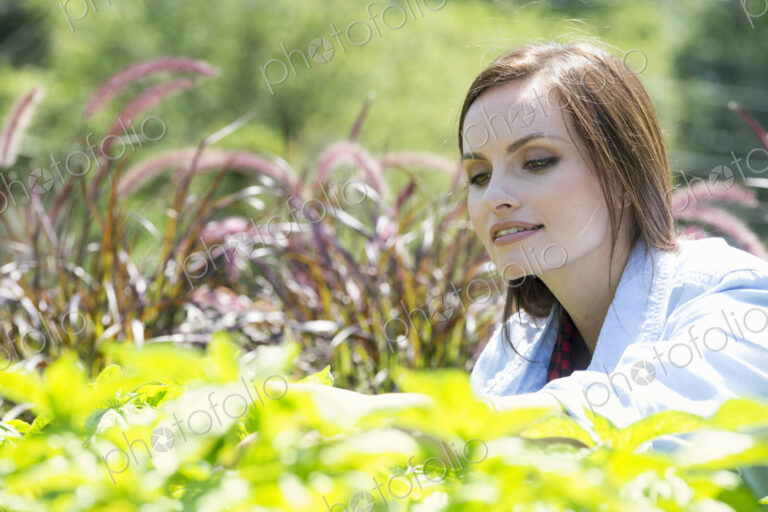 A young woman in a garden examining growing plants.