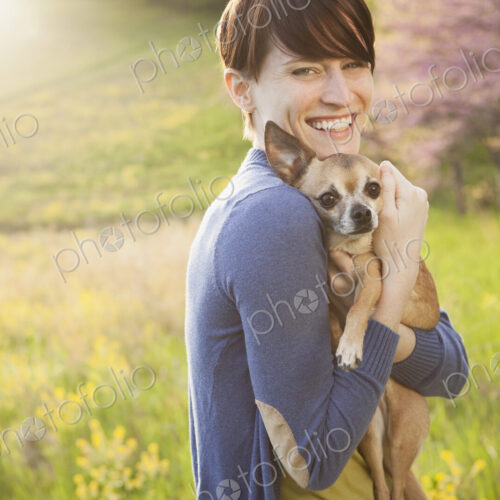 A young woman in a grassy field in spring. Holding a small chihuahua dog in her arms.… A young woman in a grassy field in spring. Holding a small chihuahua dog in her arms.…