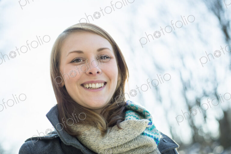 A young woman in a scarf and coat, outside on a winter day.