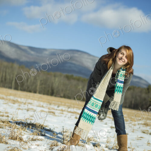 A young woman in a snowy field in a rural landscape. Scooping up snow to make a snowball. A young woman in a snowy field in a rural landscape. Scooping up snow to make a snowball.