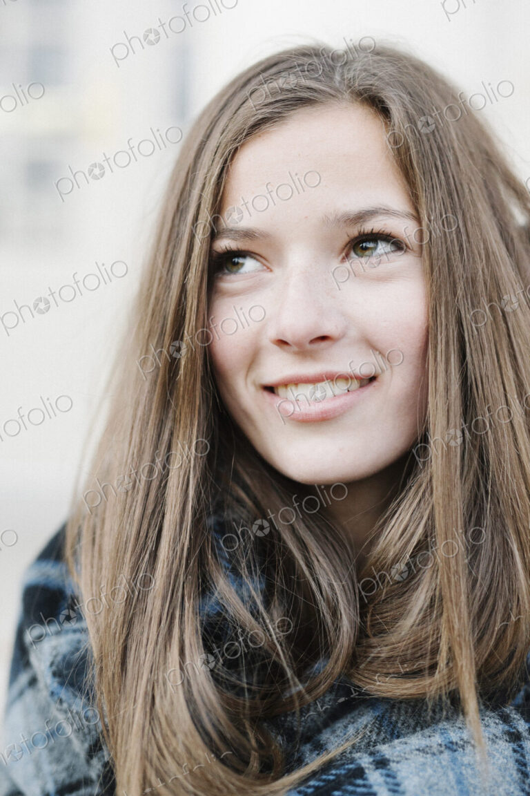 A young woman in a tartan plaid shawl outdoors in the winter.
