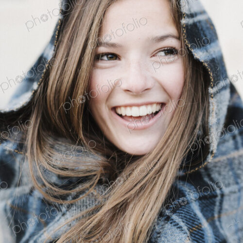 A young woman in a tartan plaid shawl outdoors in the winter.